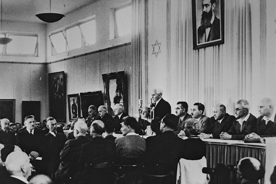 David Ben-Gurion reading Israel's Declaration of Independence beneath a portrait of Theodor Herzl, Tel Aviv, 14 May 1948.