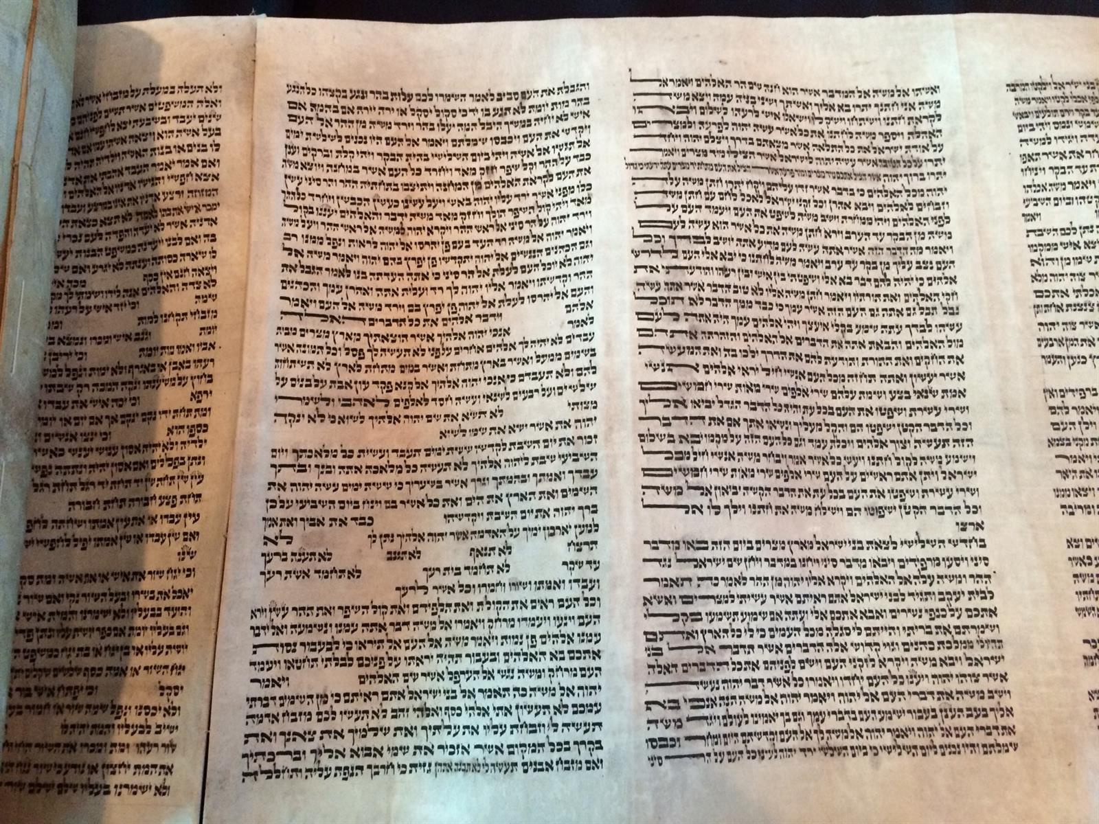An open Torah scroll, columns of Hebrew text on parchment.