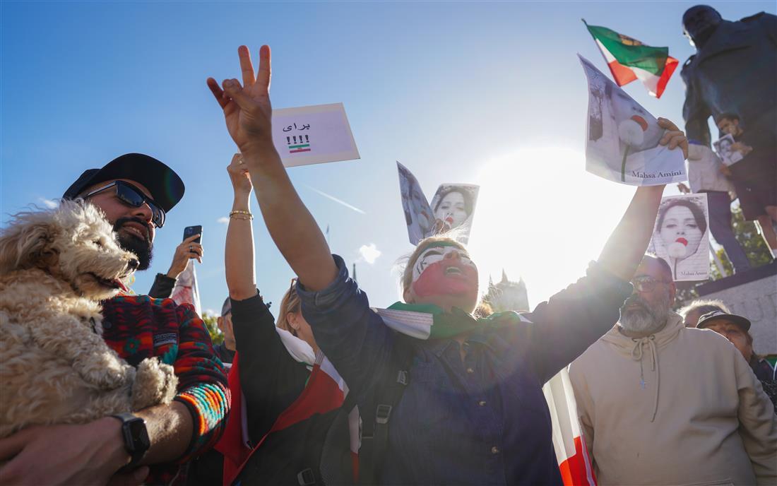 Protesters with raised fists, the Iranian flag and portraits of Mahsa Amini at a Woman, Life, Freedom demonstration in 2022.