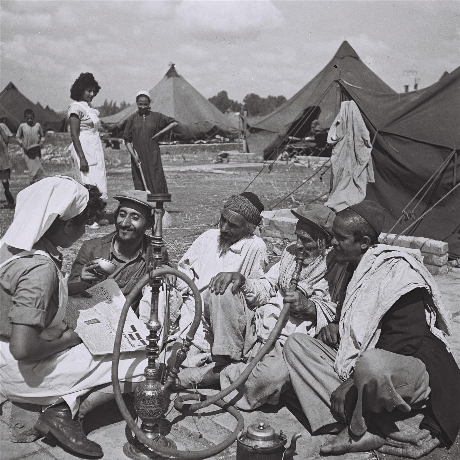 A nurse reads a newspaper to Yemenite new immigrants at the Rosh HaAyin camp in 1949.